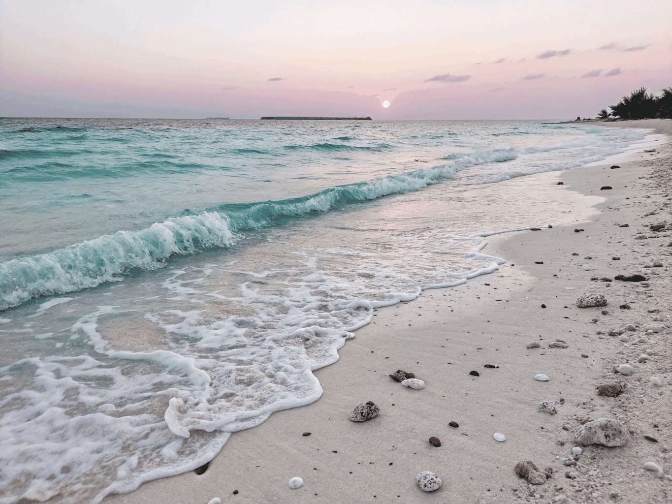 Calm turquoise ocean waves gently meeting the shore at sunrise